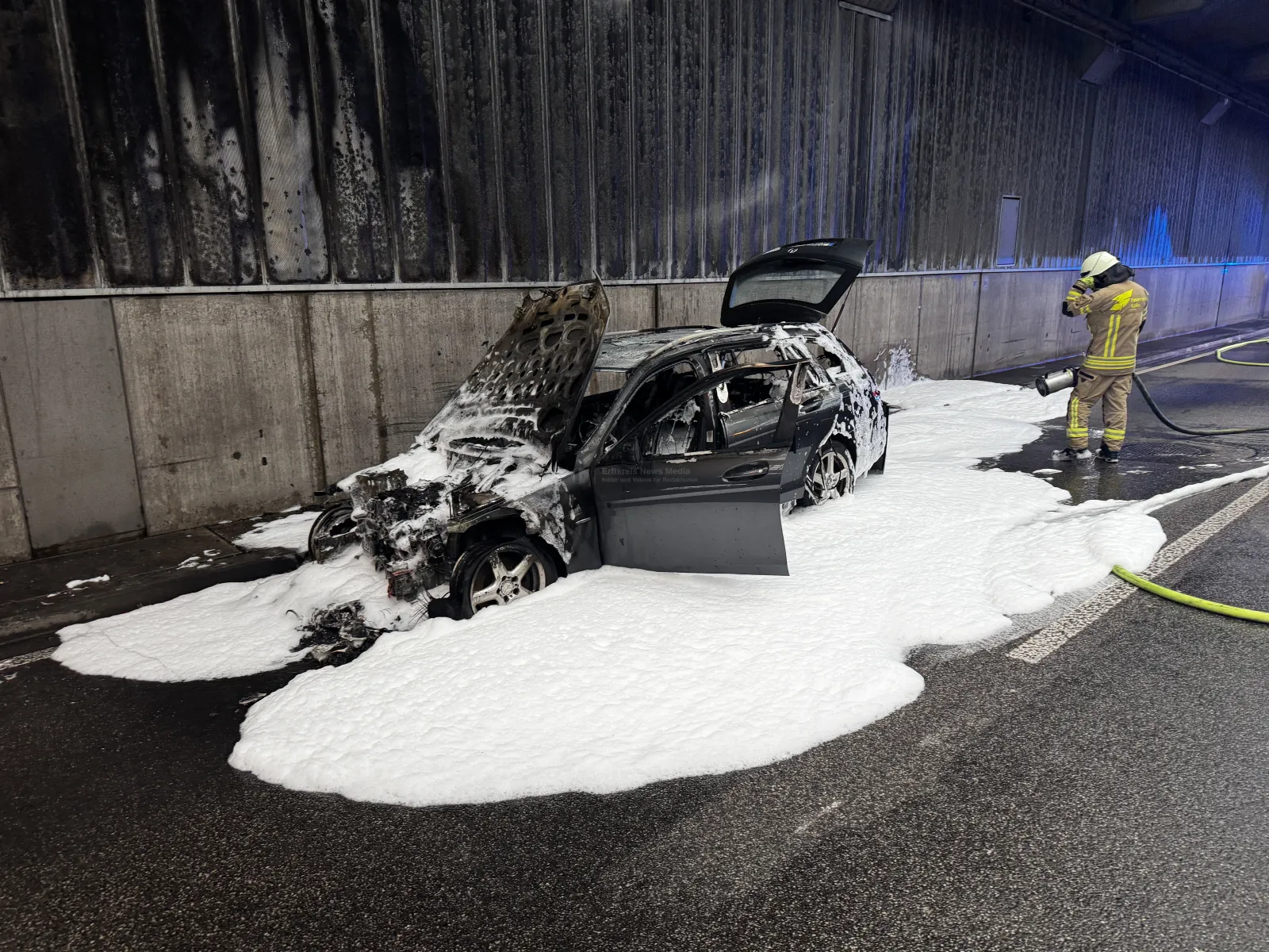 Ausgebrannter Pkw im Tunnel mit Feuerwehrschaum