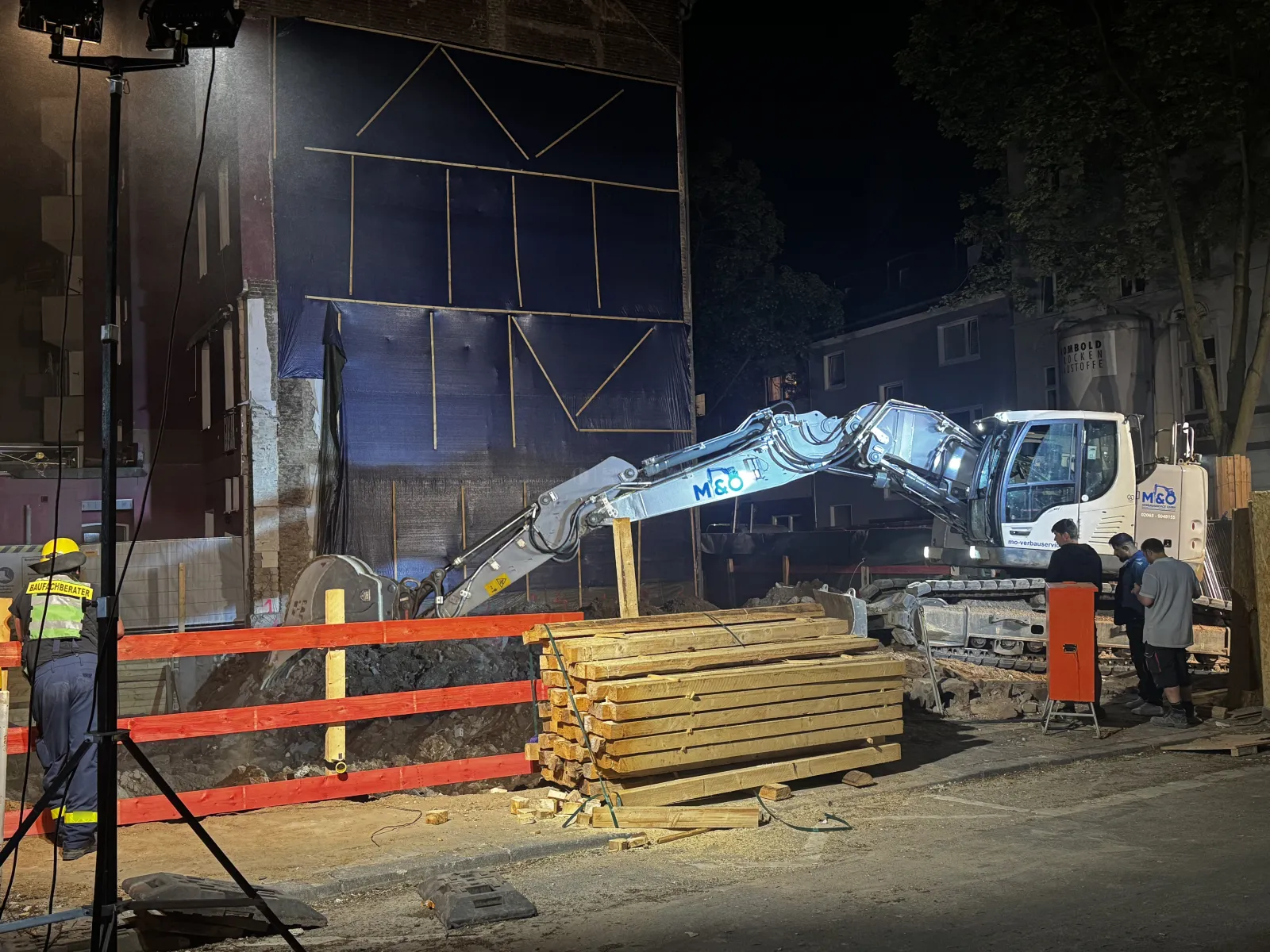 Nächtliche Baustelle mit Bagger und Fachberater