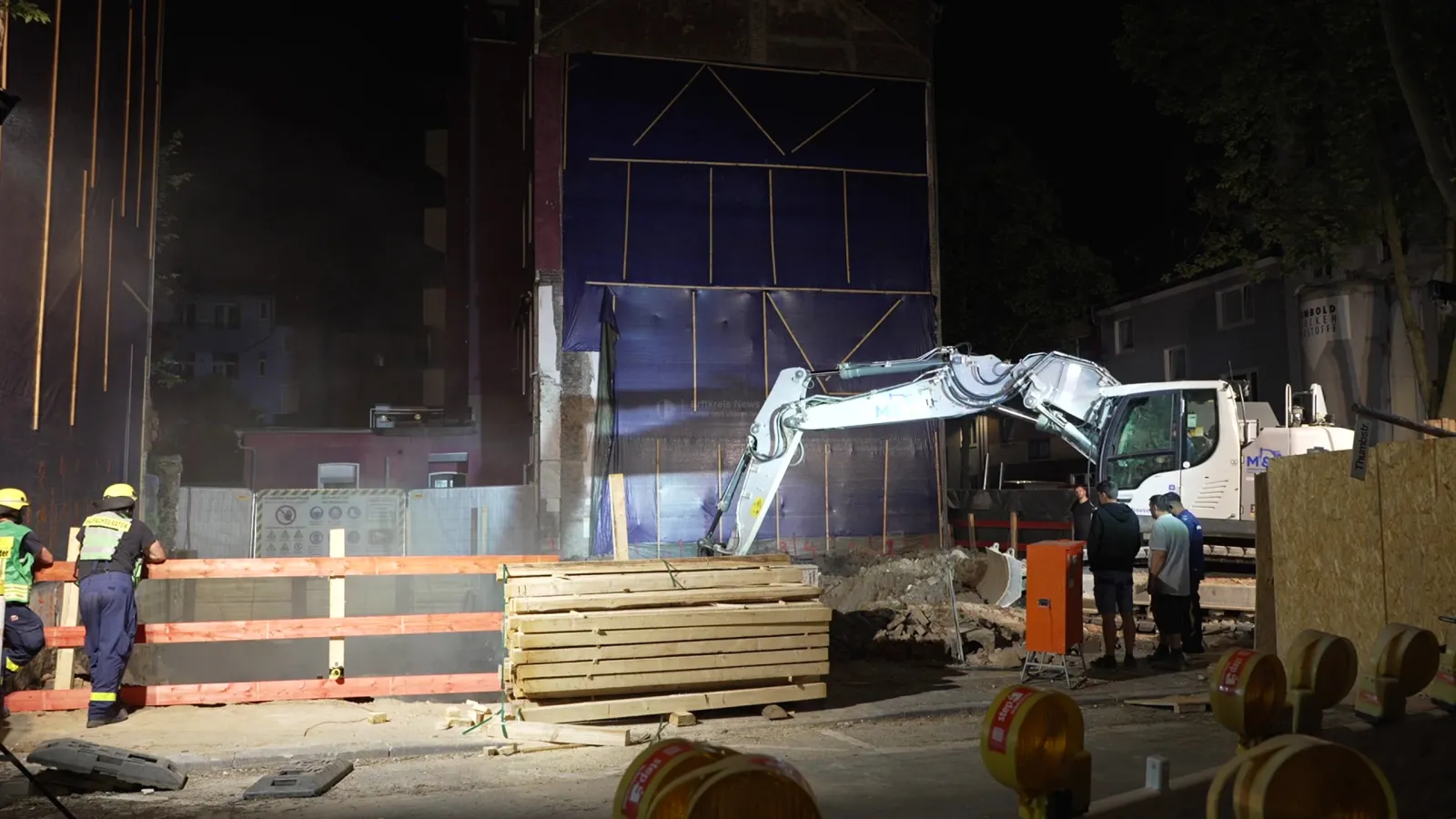 Einsatz an Baugrube mit Bagger und Einsatzkräften bei Nacht