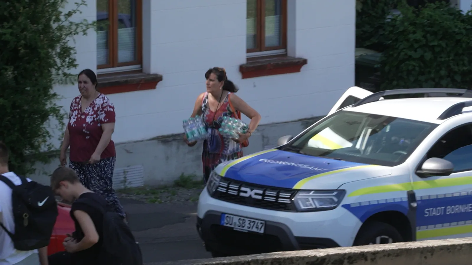 Polizeifahrzeug und Personen vor Schule