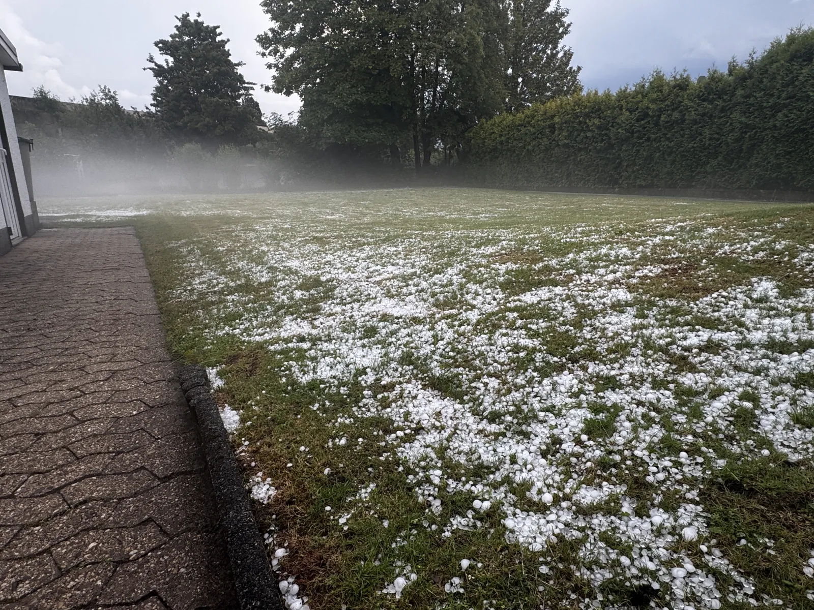 Hagelkörner auf Rasen nach Unwetter in Wesseling