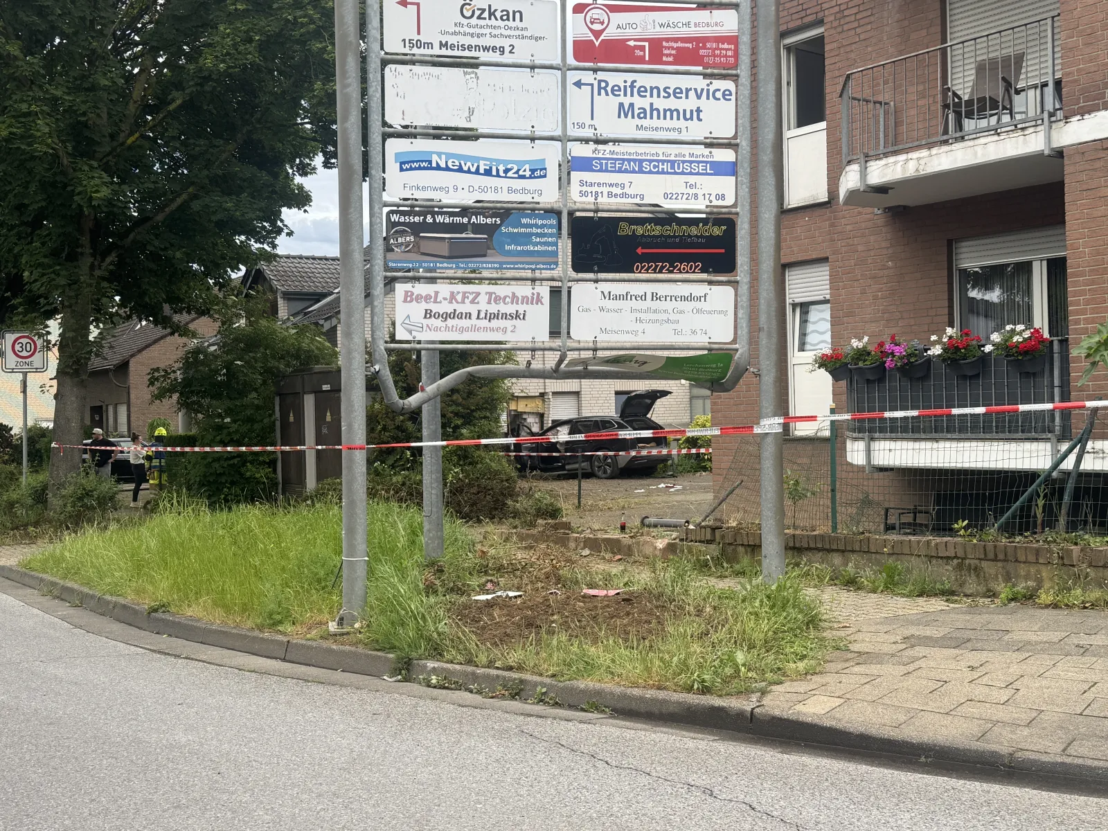 Unfallfahrzeug hinter Absperrung an Wohnhaus in Bedburg