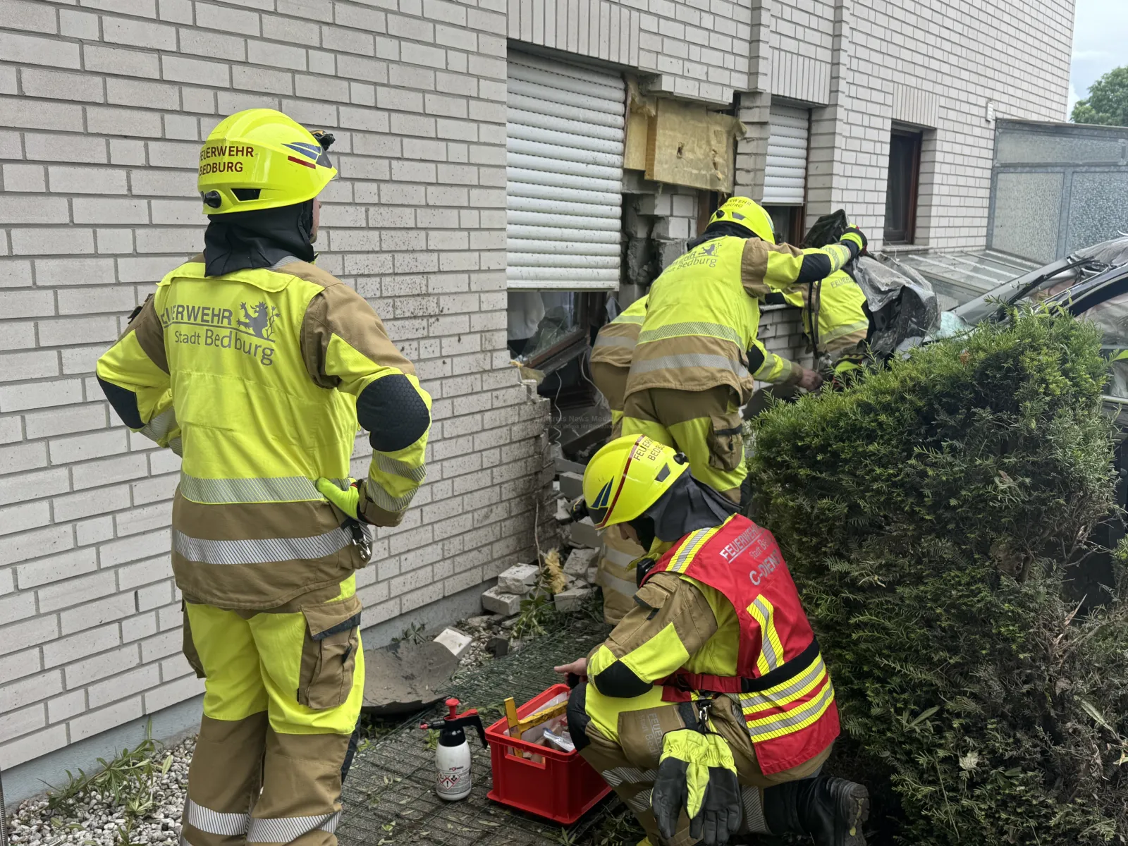 Feuerwehrleute untersuchen beschädigte Hauswand nach Unfall in Bedburg