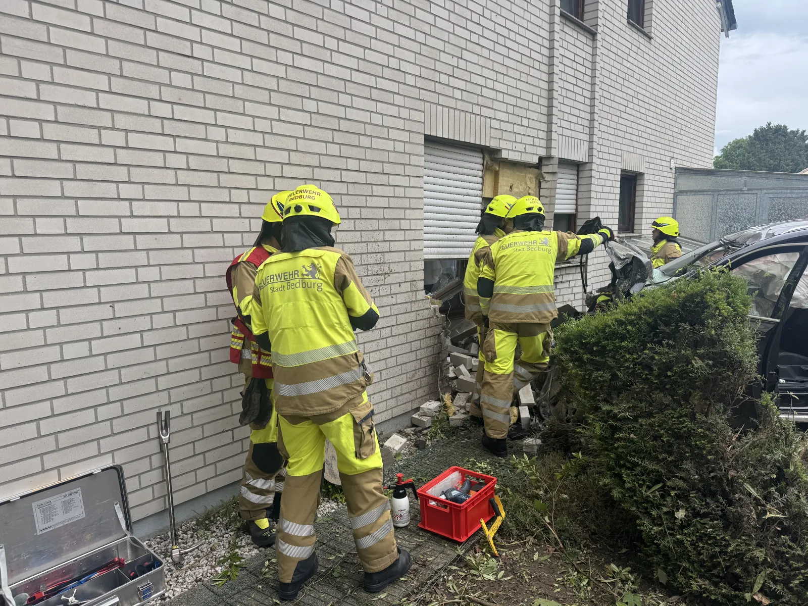 Feuerwehrleute bei Unfall mit Fahrzeuginschlag in Hauswand