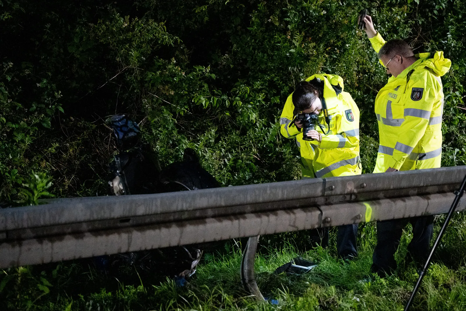 Polizeibeamte untersuchen Unfallstelle an Autobahn 555 bei Nacht