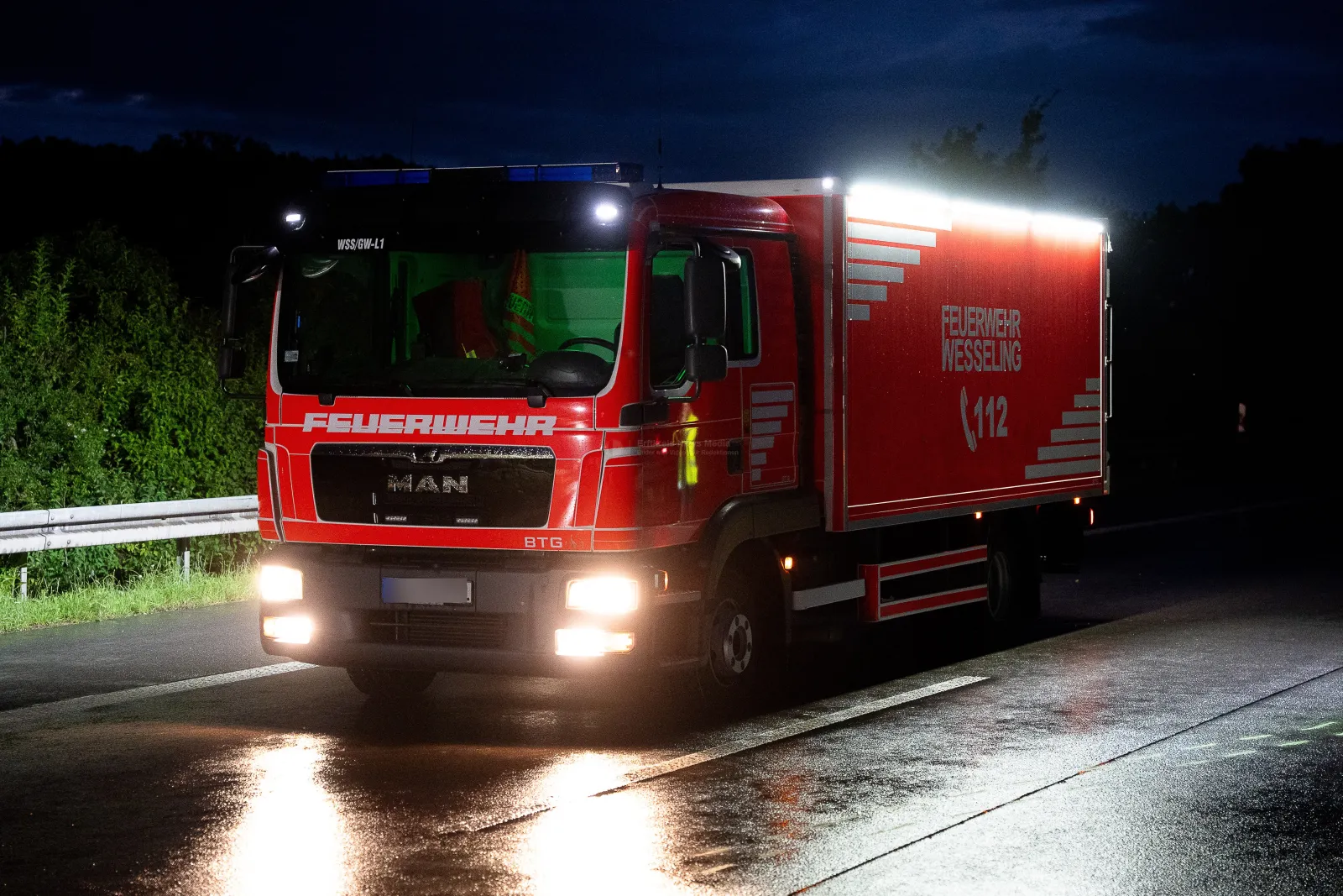 Feuerwehrfahrzeug der Feuerwehr Wesseling bei Nacht auf nasser Autobahn