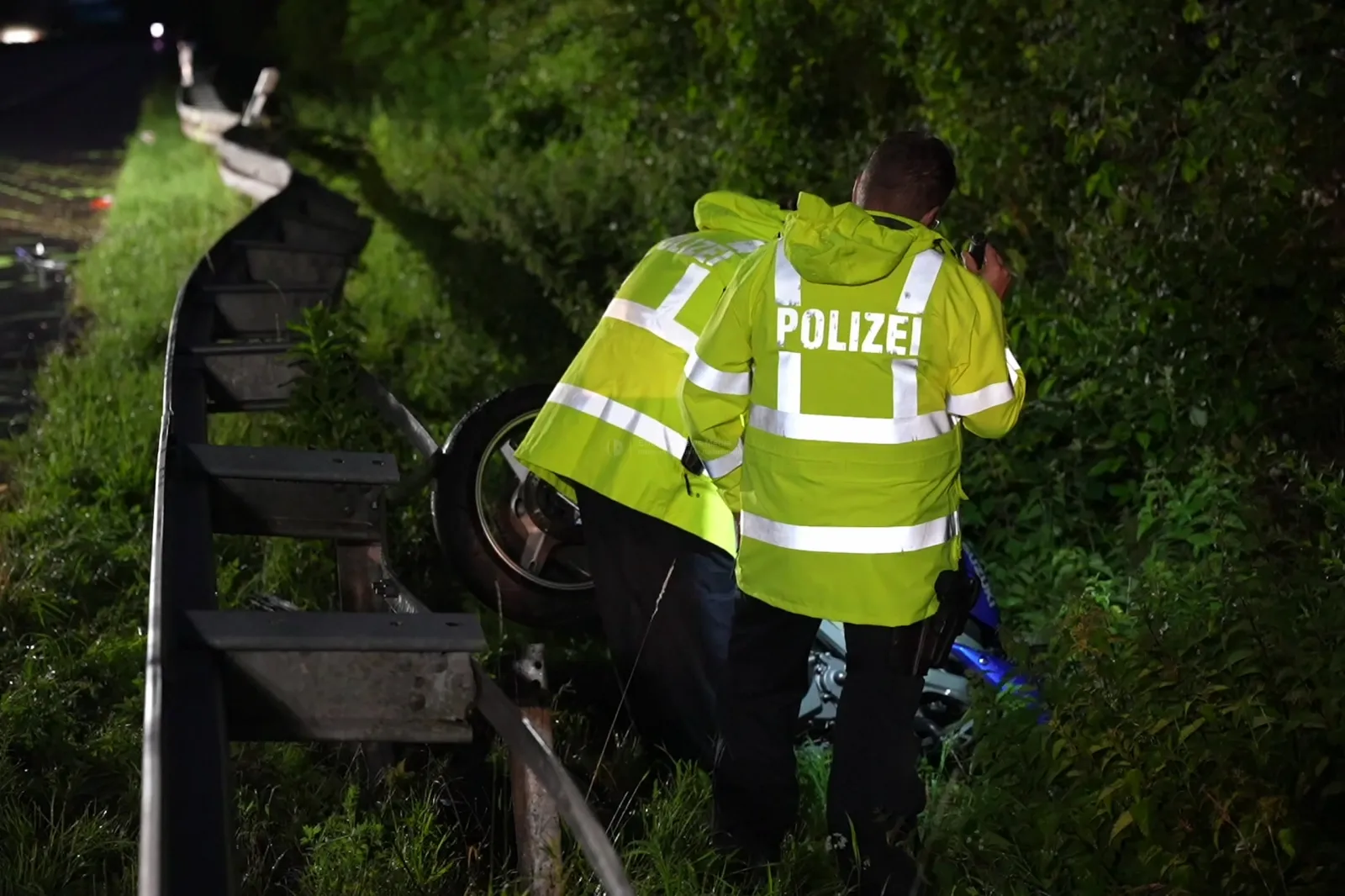 Polizisten untersuchen Motorrad nach Unfall an Leitplanke