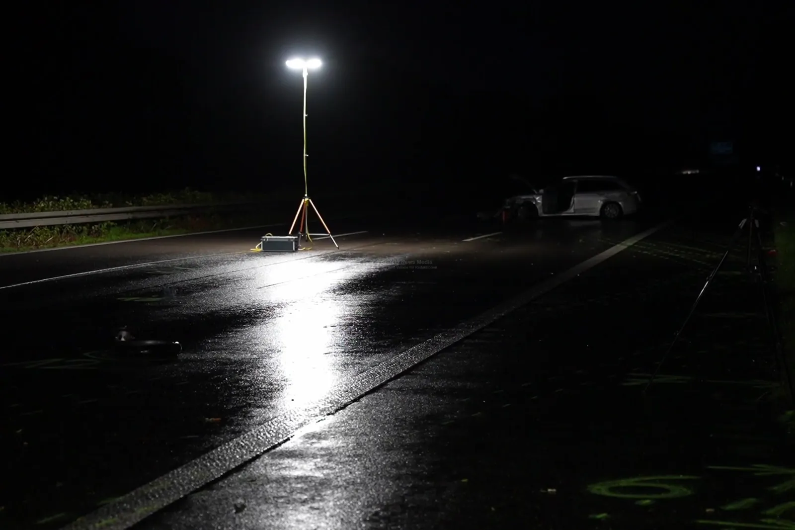 Geöffneter weißer Kombi an Unfallstelle auf nasser Autobahn bei Nacht