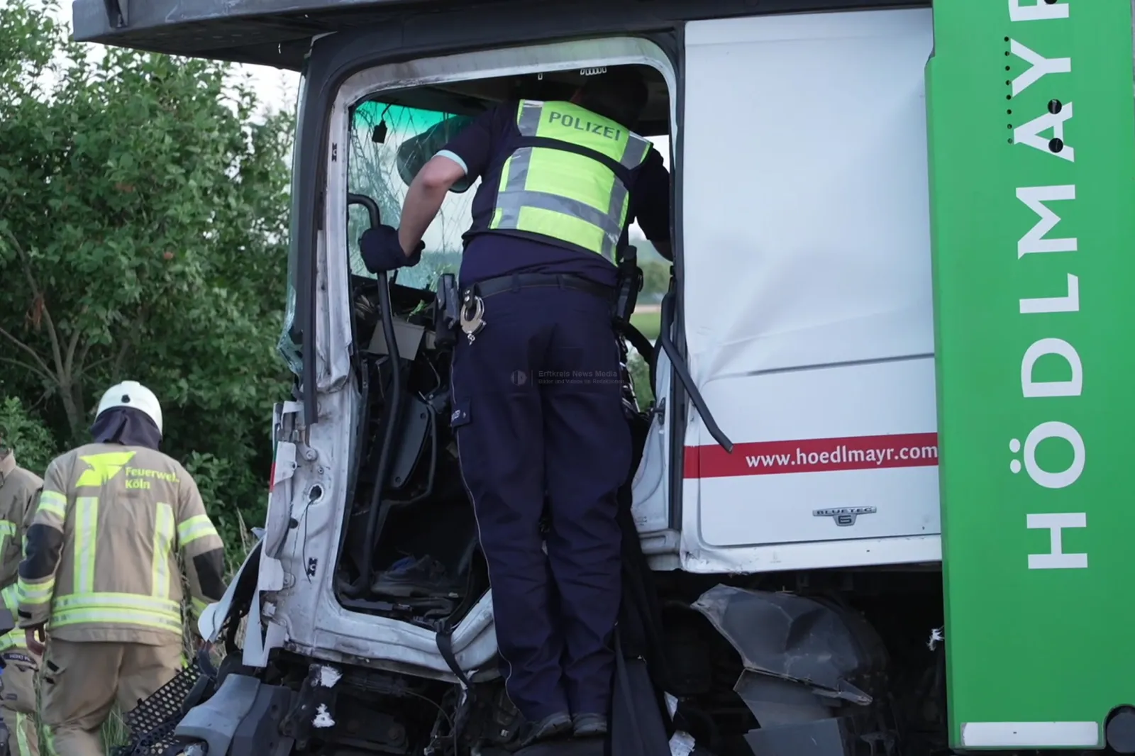 Polizeibeamter inspiziert beschädigten Autotransporter bei Unfall