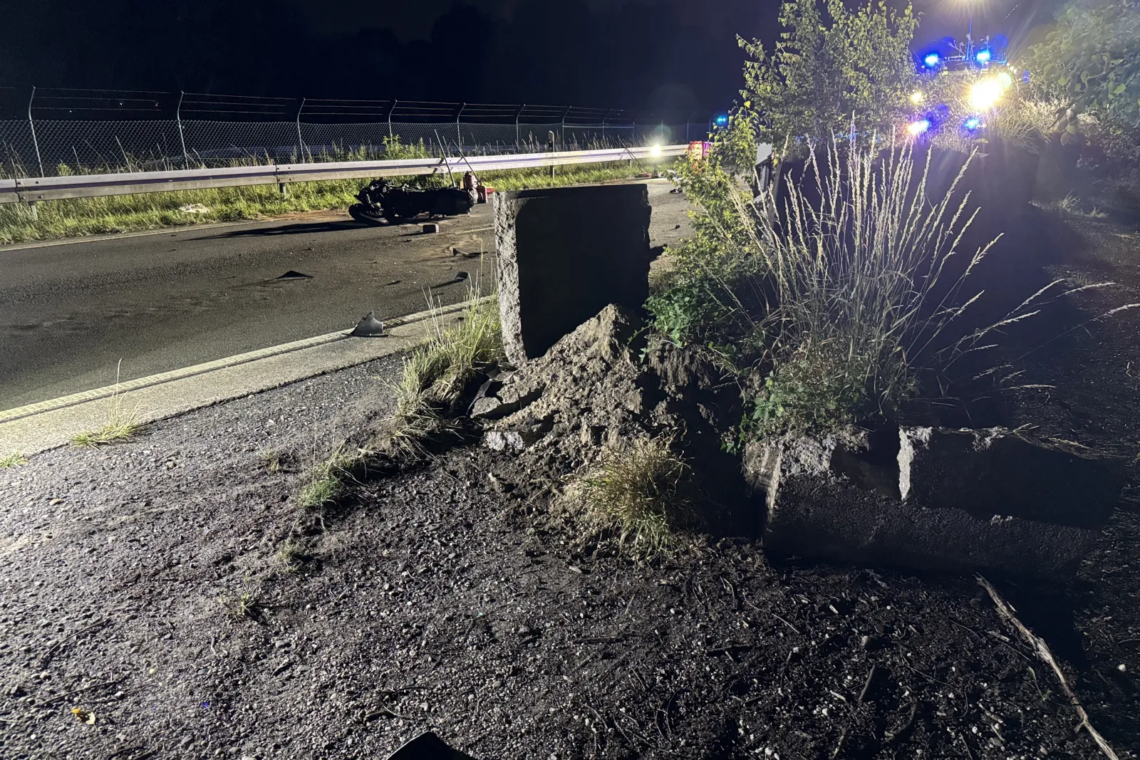 Motorrad nach Unfall auf alter Kölner Straße neben zerbrochener Betonsperre bei Nacht