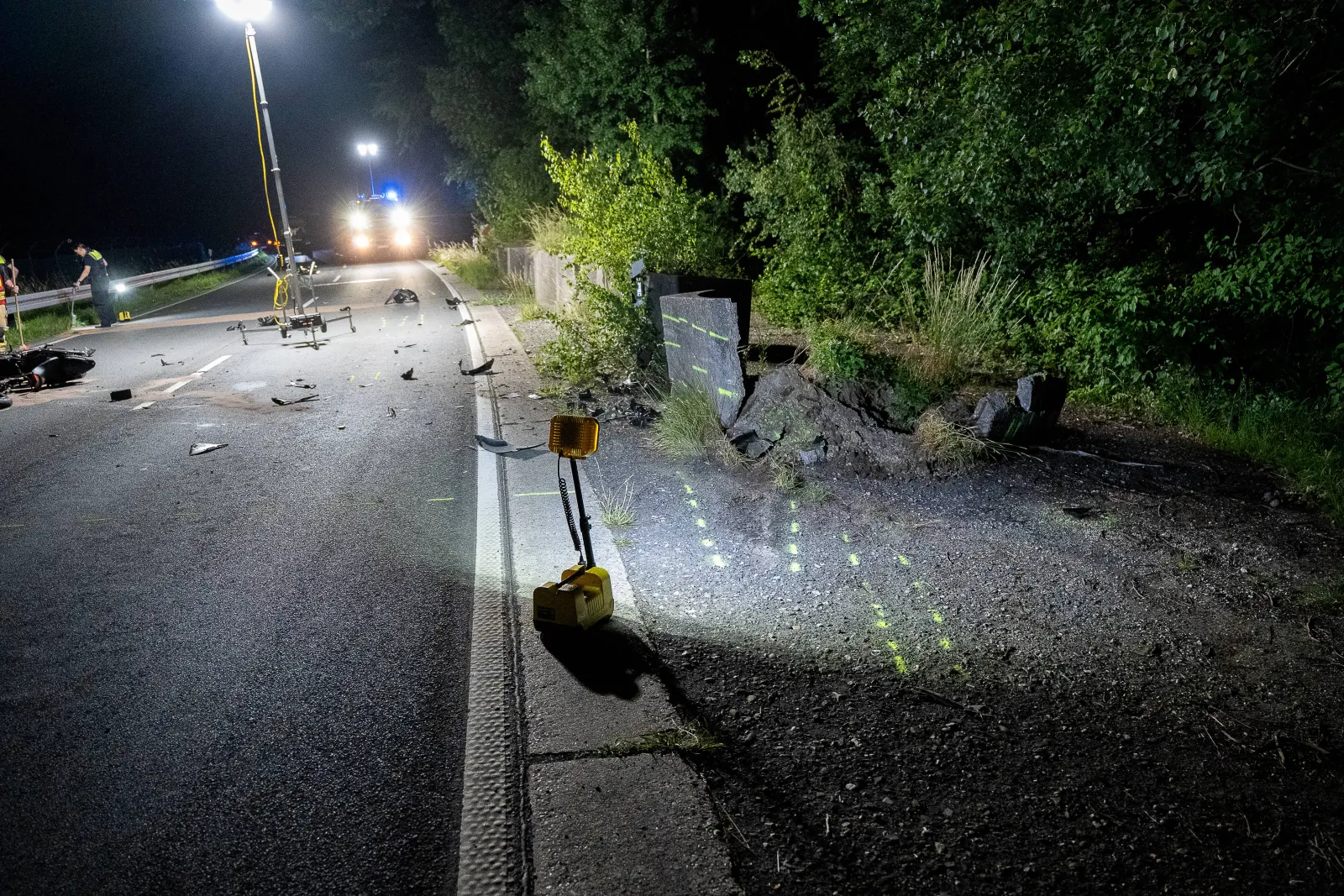 Unfallstelle eines Motorradunfalls an Betonsperre nachts auf Landstraße