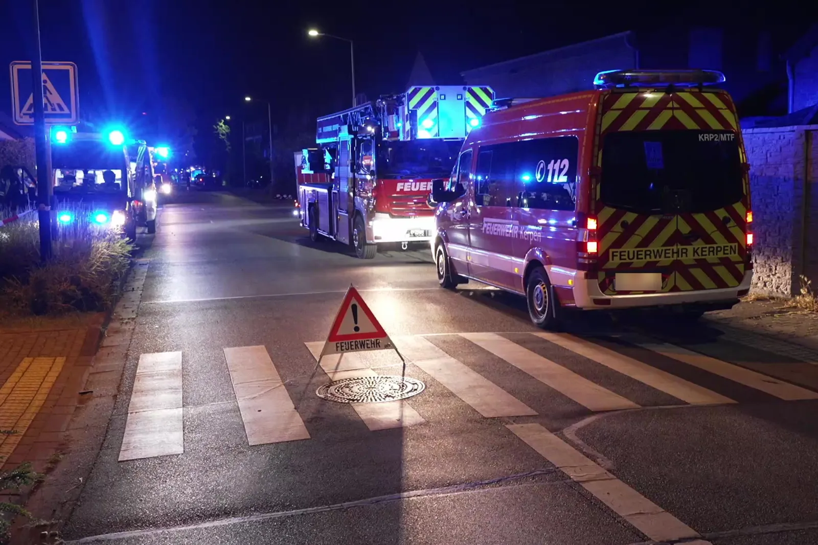 Feuerwehrfahrzeuge und Warnschild bei Nacht in Kerpen-Sindorf