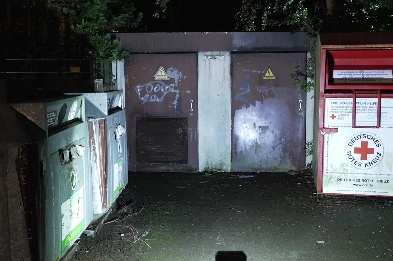 Trafostation mit Müllcontainern und Altkleider-Container des Roten Kreuzes bei Nacht