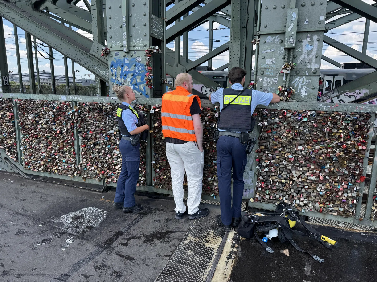 Polizeibeamte und Einsatzkraft auf Hohenzollernbrücke neben Liebesschlössern