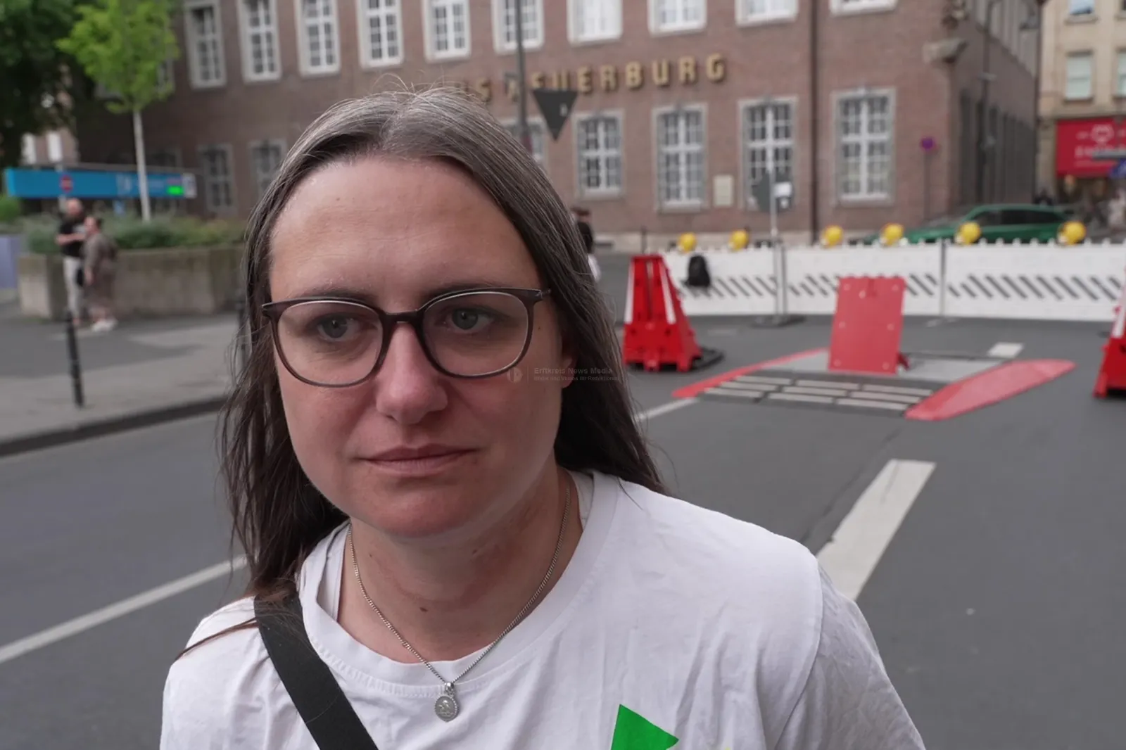 Frau mit Brille und weißem T-Shirt auf Straße in Köln