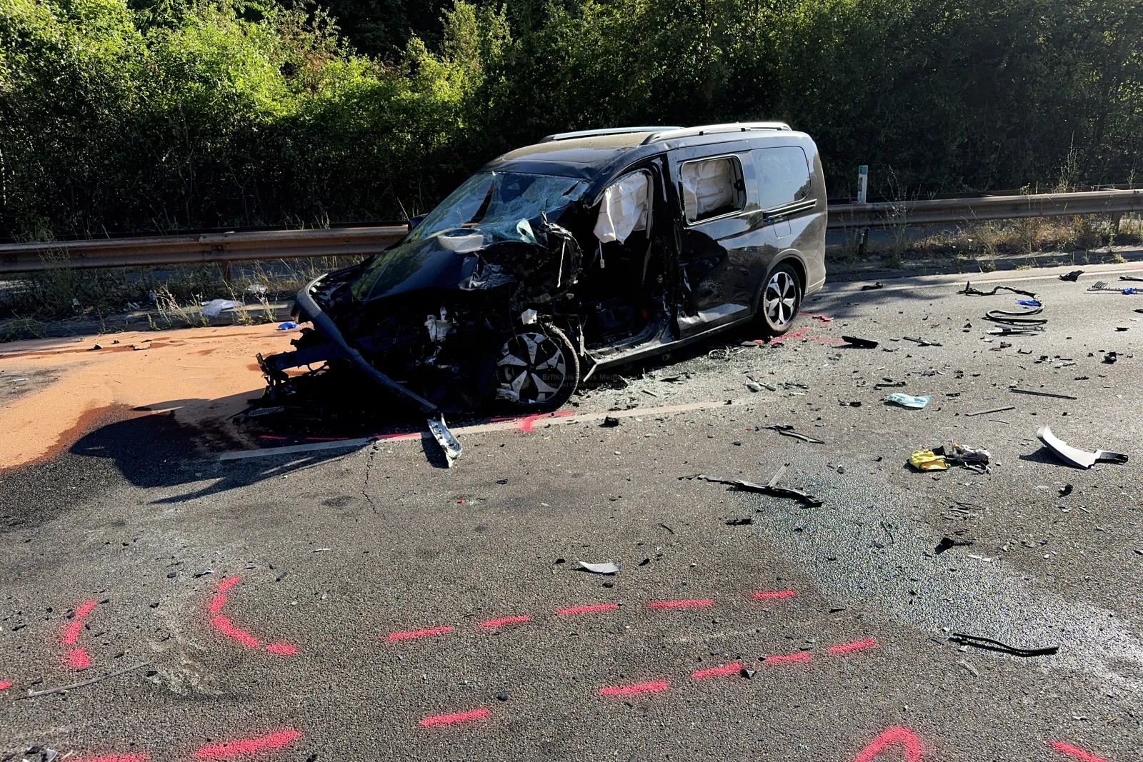 Schwer beschädigter schwarzer Van nach Unfall auf Straße