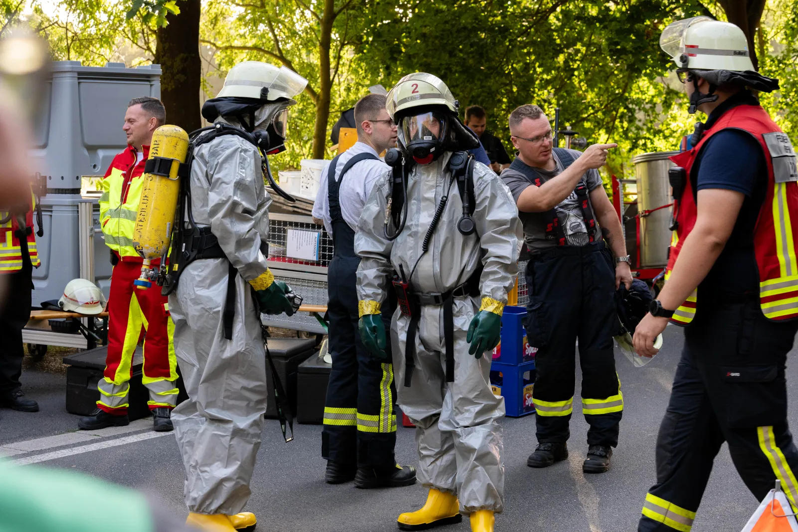 Feuerwehrleute und Einsatzkräfte in Schutzanzügen bei Container-Unfall auf der L163