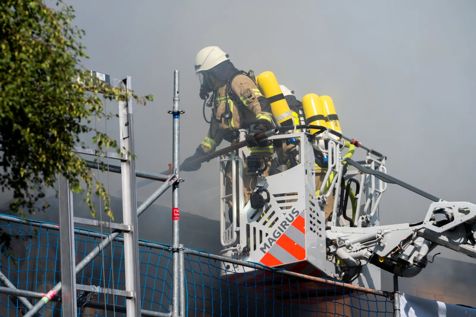 Feuerwehrmann in Atemschutzausrüstung auf Magirus-Drehleiter bei Brandbekämpfung