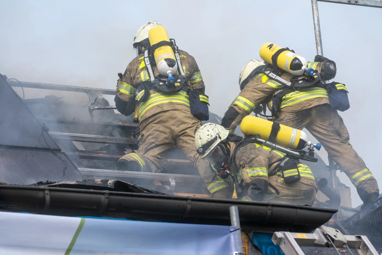 Feuerwehrleute bekämpfen Brand an Dach mit Fotovoltaikanlage in Köln