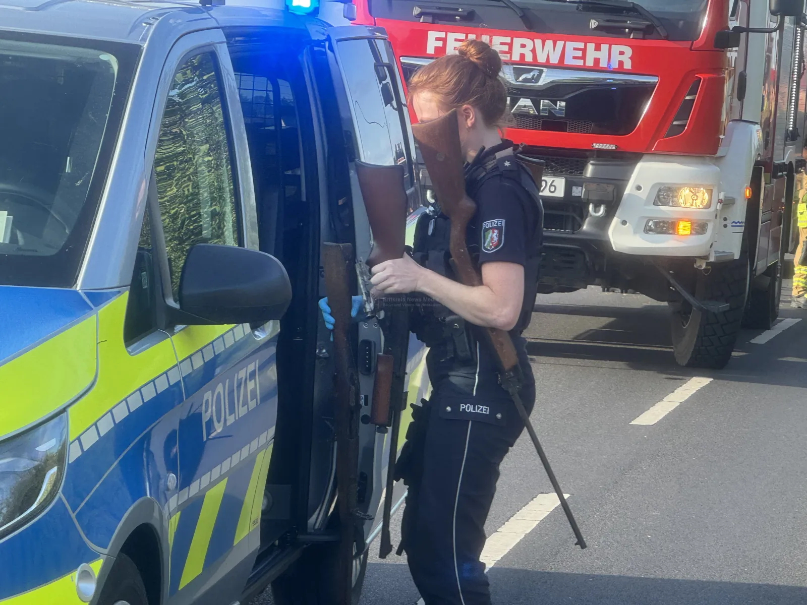 Polizeibeamtin mit Gewehren vor Polizeiwagen bei Stoppelfeldbrand in Köln