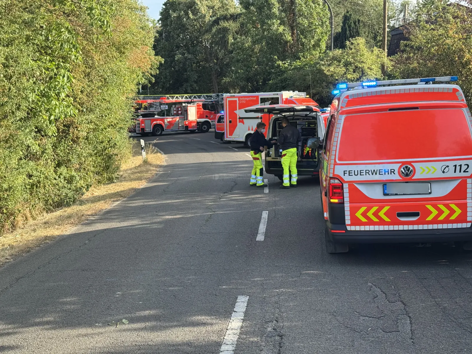 Feuerwehrfahrzeuge und Einsatzkräfte bei Stoppelfeldbrand in Köln Immendorf