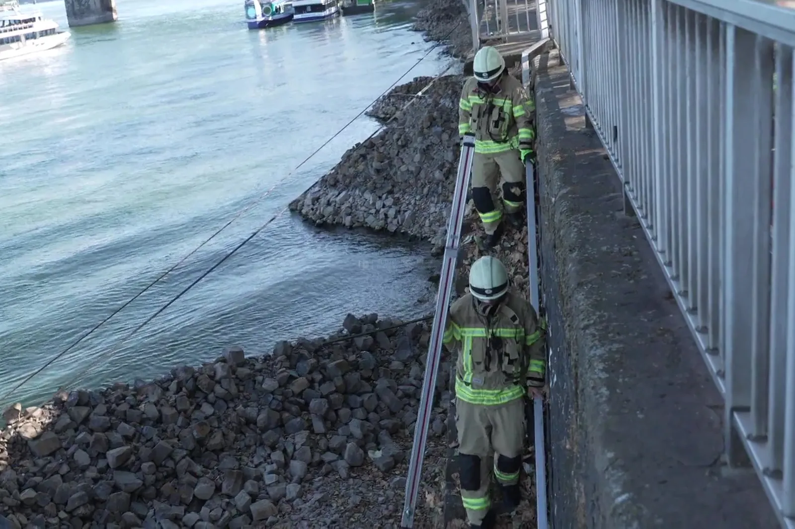 Feuerwehrmänner tragen Leiter am Rheinufer in Köln