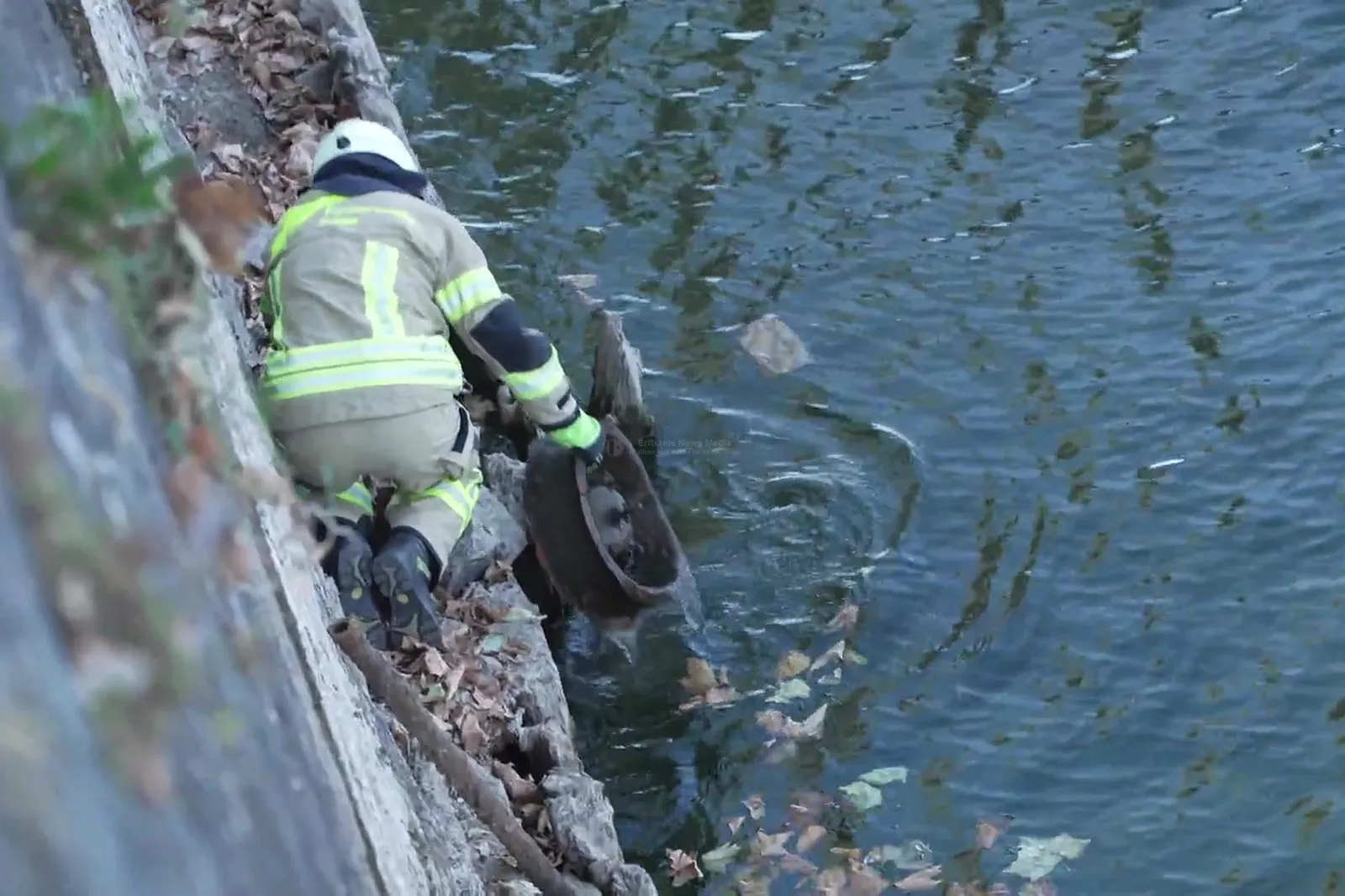 Feuerwehrmann hebt Schiffsturbine am Rheinufer aus dem Wasser