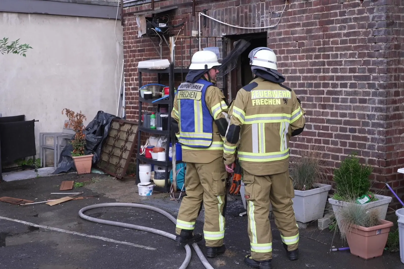Feuerwehrleute vor Imbiss mit Schläuchen und Ausrüstung